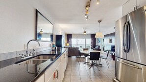 Eine moderne Küche mit einem Edelstahl-Kühlschrank, einer schwarzen Arbeitsplatte und einem Essbereich mit Tisch und Stühlen.