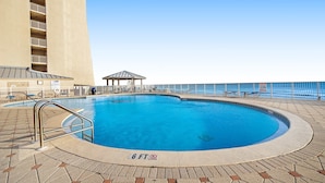 Ein Pool mit einer maximalen Tiefe von 6 Fuß, umgeben von einer gefliesten Terrasse und einem Gebäude mit Balkonen.