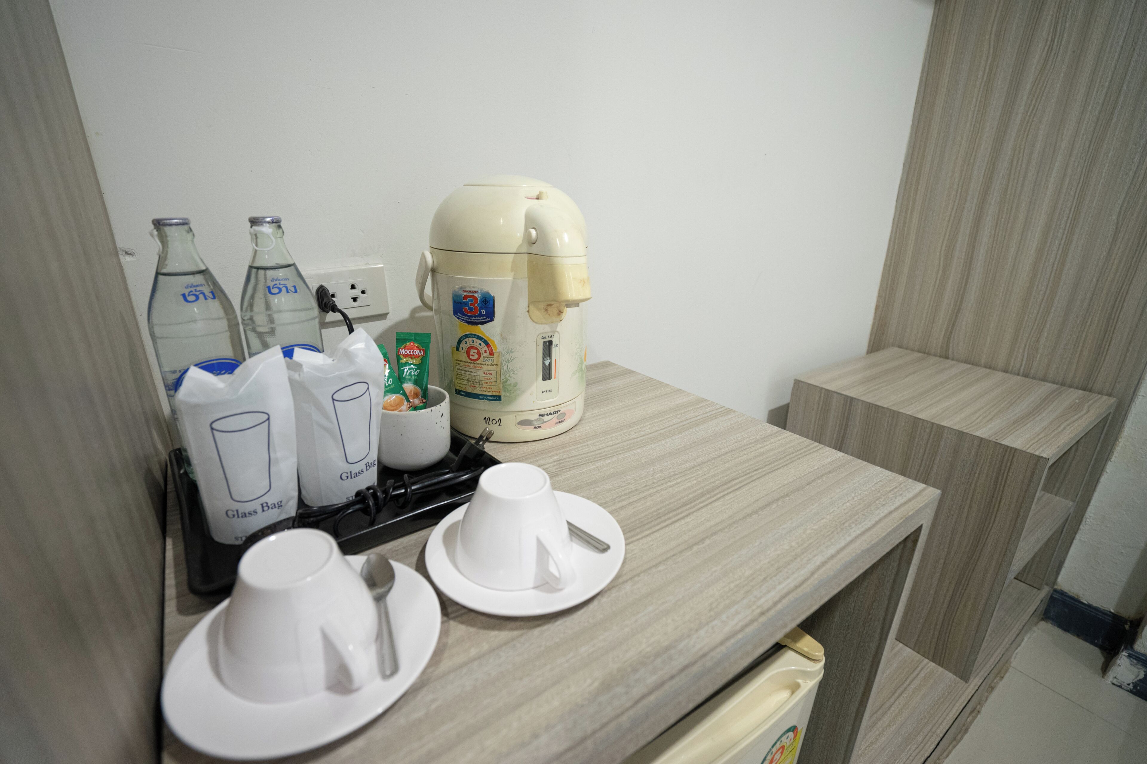 A kitchenette with a coffee maker, glass bags, and bottles.