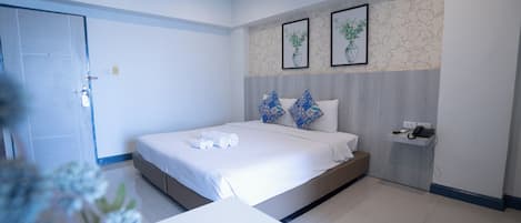 Habitación de hotel moderna con una cama grande, una mesita de noche, un teléfono en la pared y obras de arte enmarcadas.