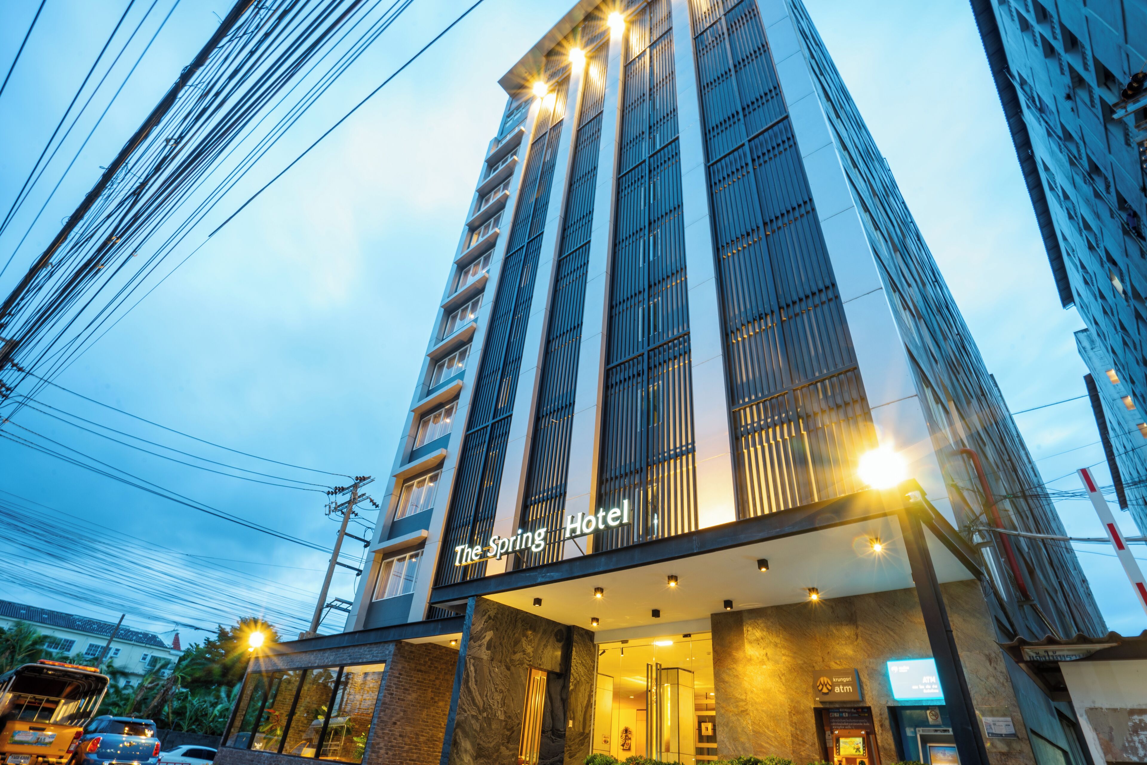 Un hôtel moderne, doté d’une entrée imposante et d’une enseigne indiquant « The Spring Hotel ».