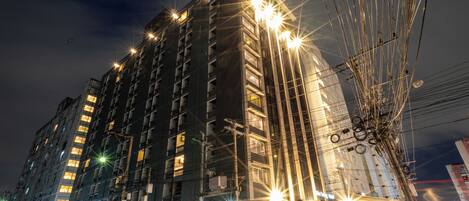 A multi-story building with illuminated windows and a busy street below.