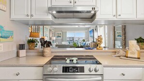 Una cocina moderna con armarios blancos, electrodomésticos de acero inoxidable y vista al área de estar.