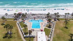 Un resort con piscina central, acceso a la playa y palmeras.