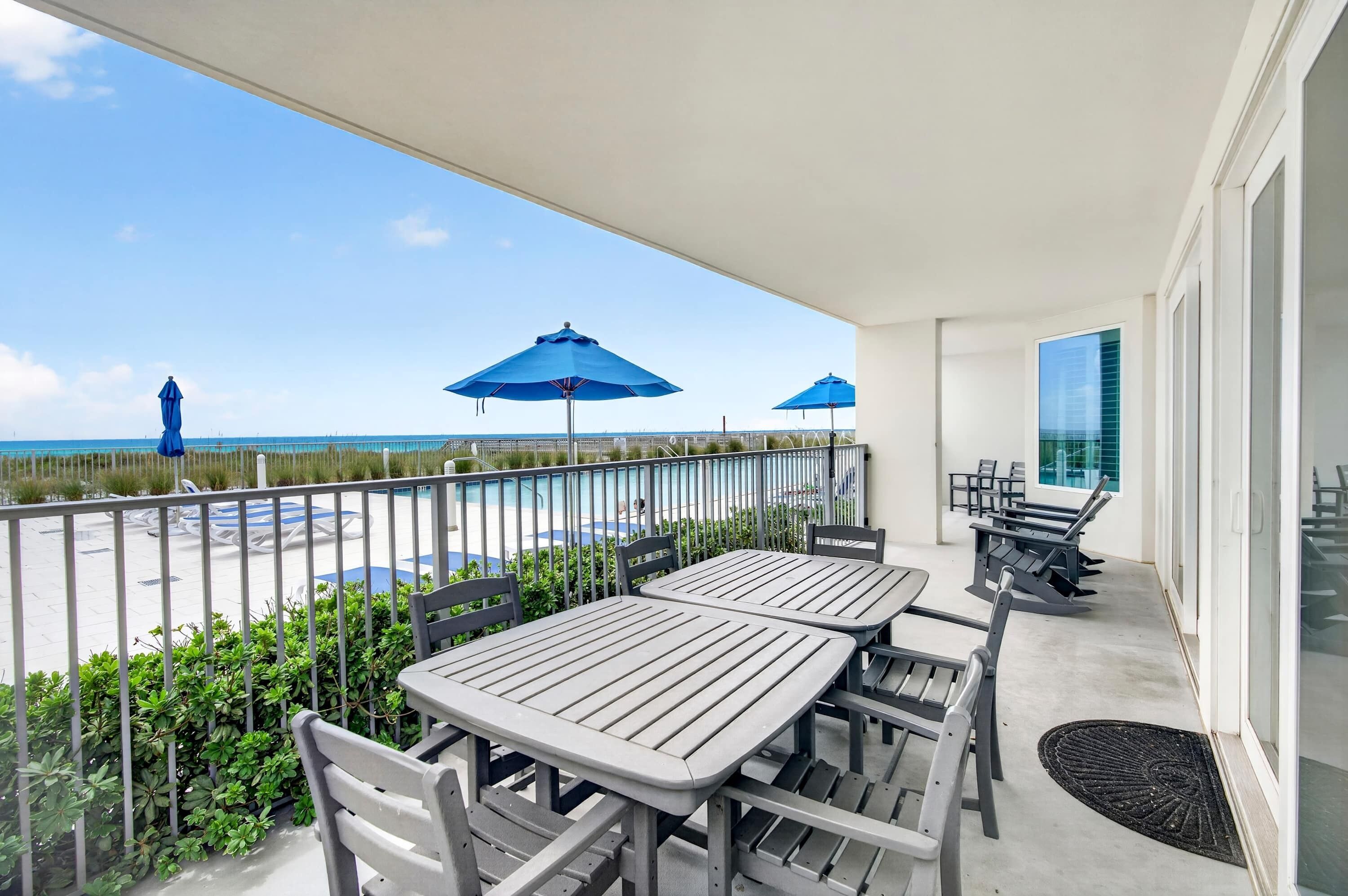 Un balcón con mobiliario exterior, piscina y vista a la playa.