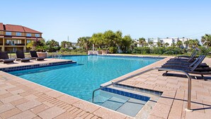 En pool med solstolar och en kakelbeklädd poolterrass.