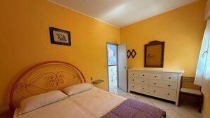 Ein Schlafzimmer mit Bett, Schminktisch, Spiegel und einer Tür zum Balkon.