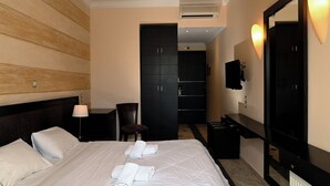 Ein Hotelzimmer mit Bett, Schreibtisch, Stuhl, Kleiderschrank und Fernseher.