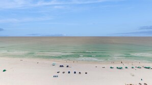 A beach with a clear sky, calm sea, and several umbrellas and beach chairs. - 15th Floor Stunning Condo, Splash pad w multiple pools & hot tub (Destin)