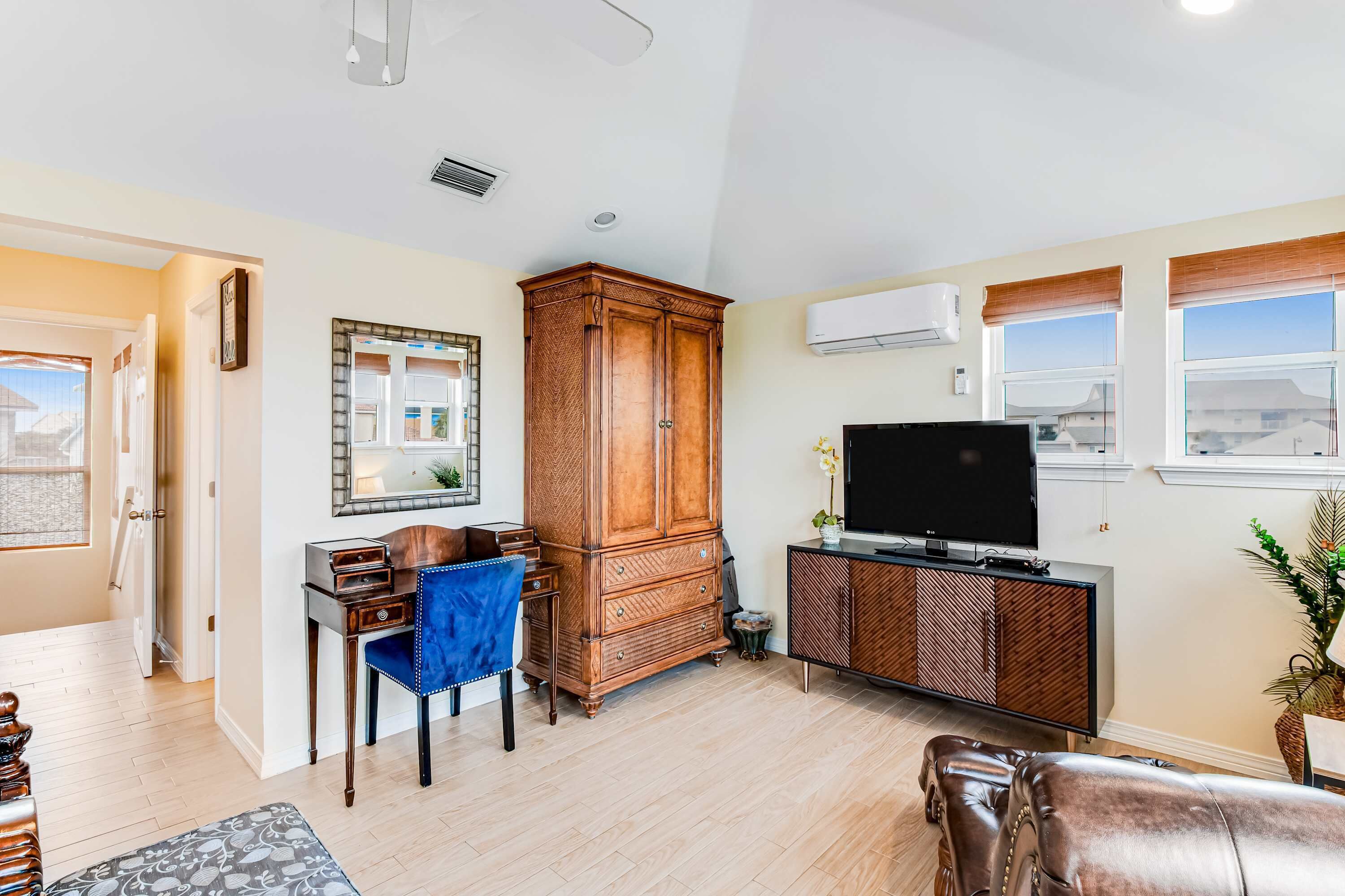 A living room with a wooden cabinet, a TV, a blue chair, and a leather sofa.