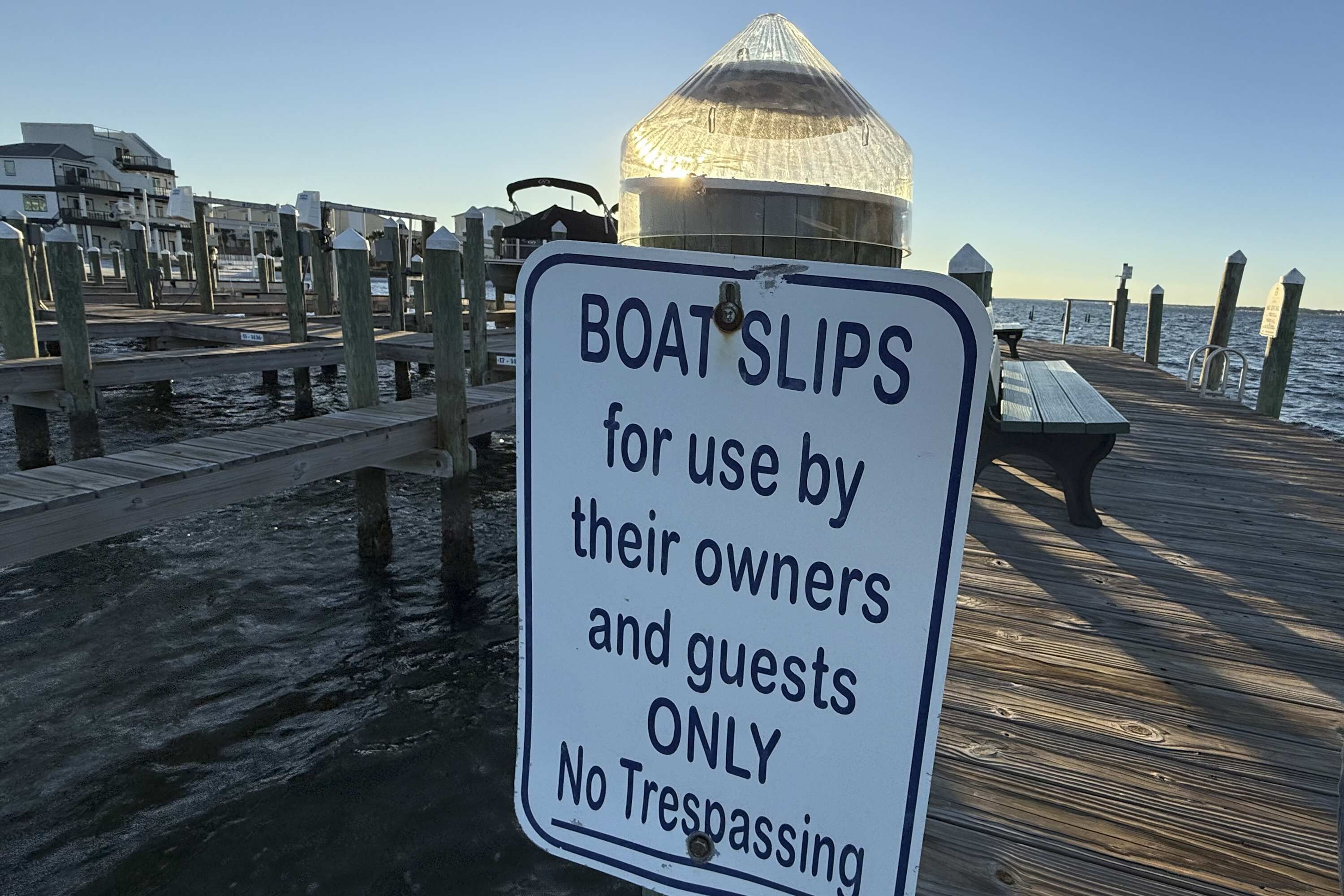 Cartel en un muelle que indica espacios para embarcaciones reservados para propietarios e invitados, prohibido el acceso.