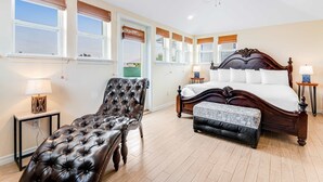 Een slaapkamer met een groot bed, een leren fauteuil, een houten bankje en een plafondventilator.