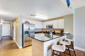Una cocina moderna con armarios blancos, electrodomésticos de acero inoxidable y una isla central con taburetes de bar.