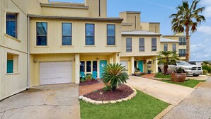 A row of townhouses with a garage, a small garden, and a palm tree. - Sound view townhome with balcony, alfresco dining, AC, & W&D - snowbird-friendly (Navarre)
