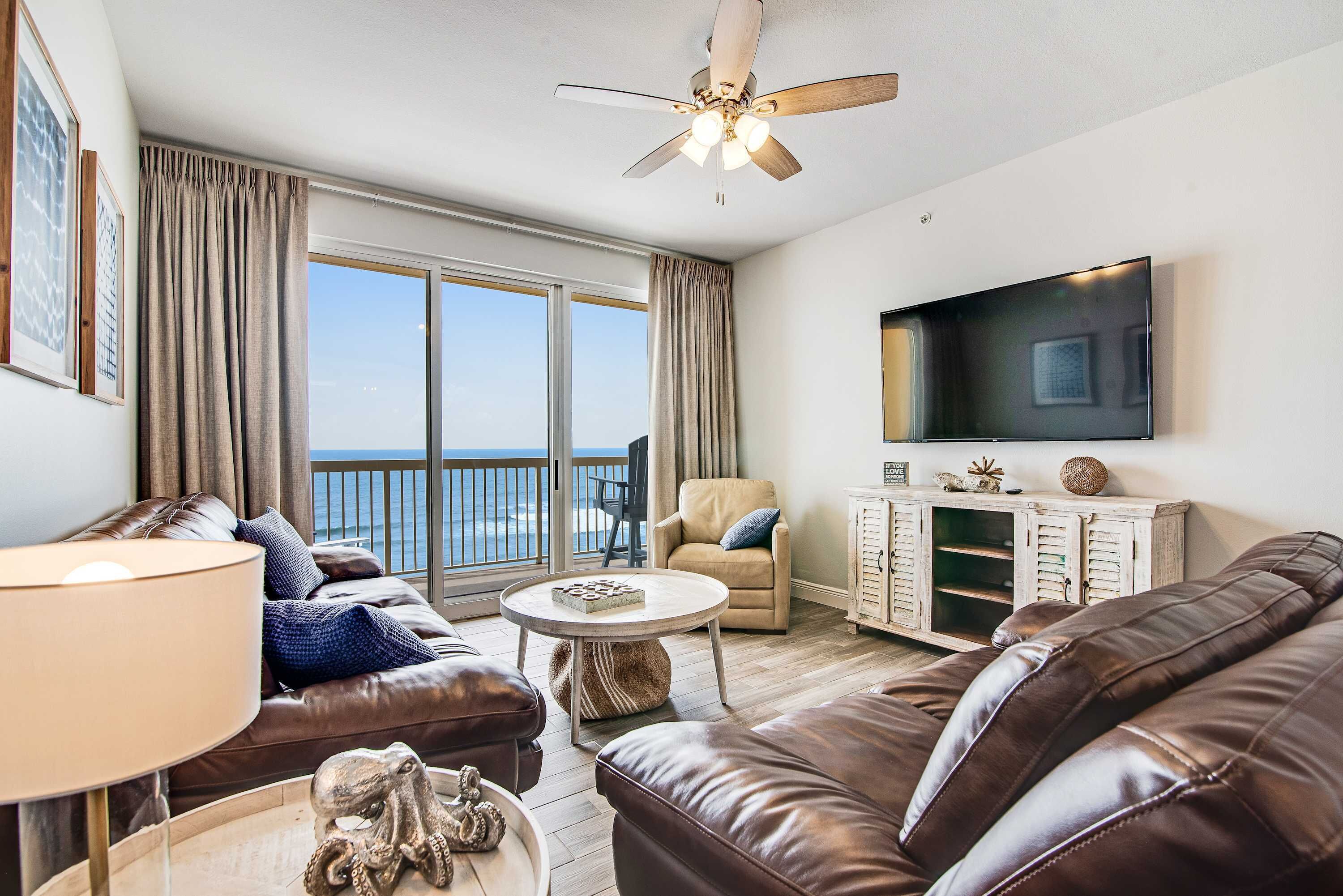 A living room with a sofa, a coffee table, a TV, and a balcony with a view.