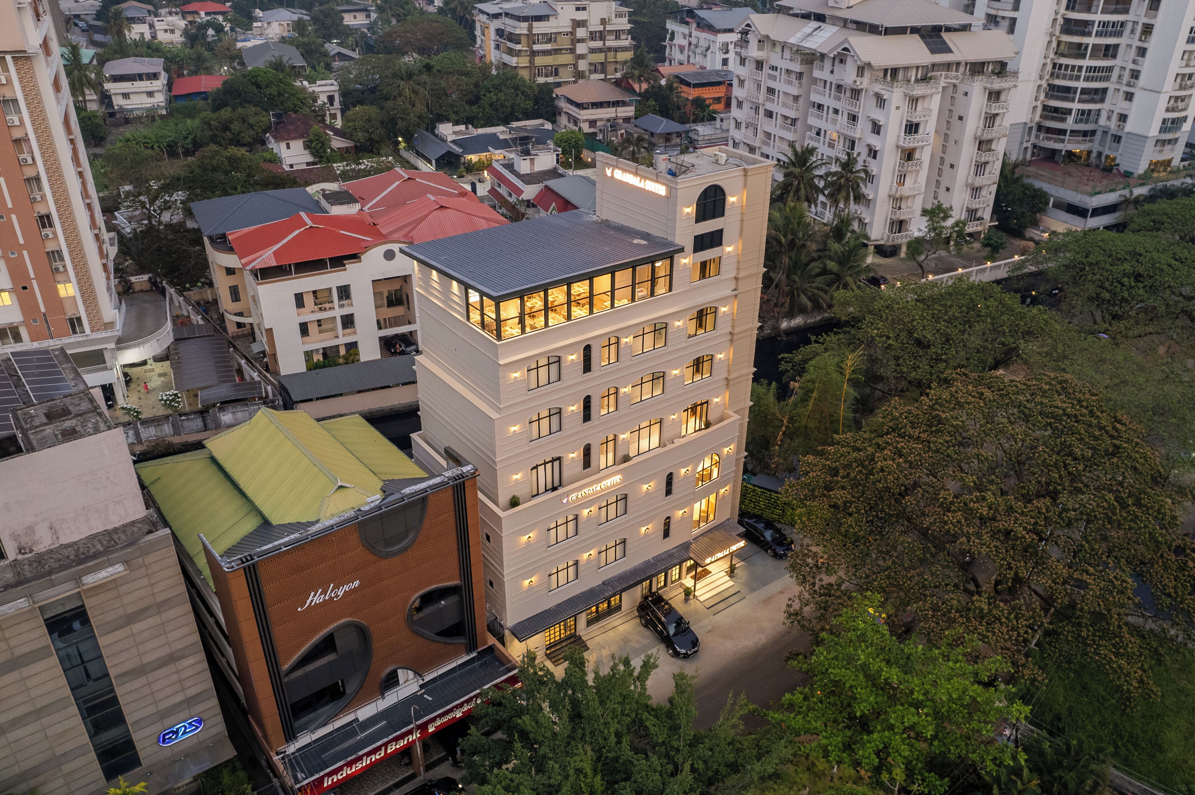 A multi-story hotel with a flat roof, large windows, and a parking area.