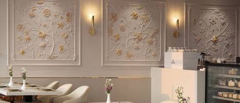 A modern dining area with white chairs, tables, and decorative wall panels.