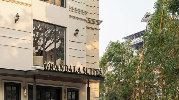 Ein Gebäude mit der Aufschrift "GRANDALAS SUITES" und einem schwarzen Auto davor.