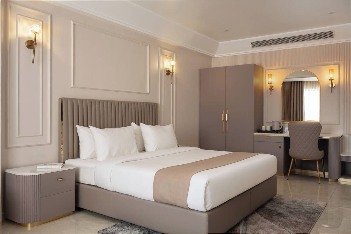 Une chambre d’hôtel moderne, dotée d’un grand lit, de tables de chevet, d’un bureau et d’une chaise.