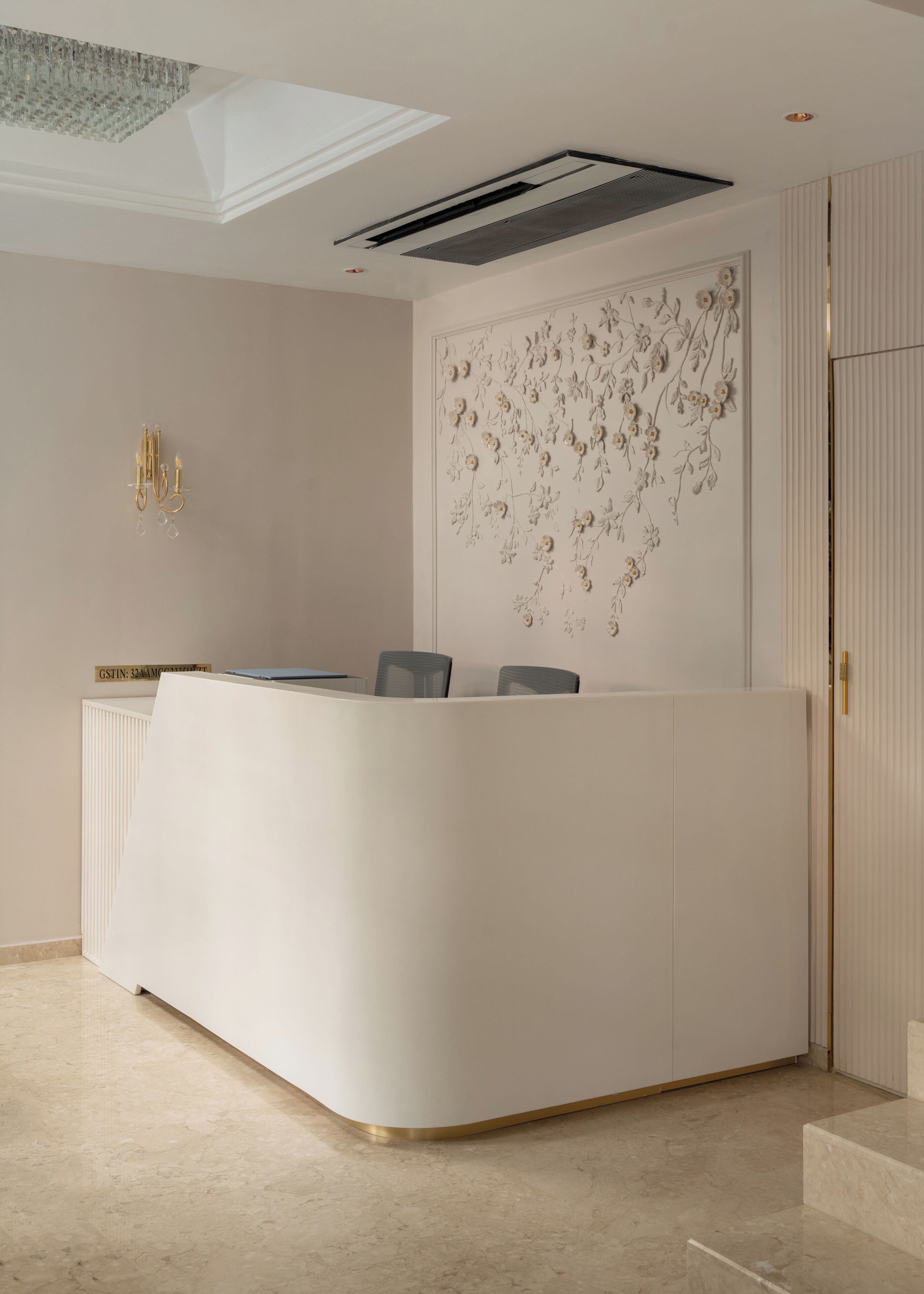 A reception desk with a modern design, a ceiling light fixture, and a decorative wall panel.