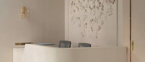 A reception desk with a modern design, a ceiling light fixture, and a decorative wall panel.