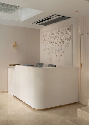 En receptionsdisk med moderne design, en loftlampe og en dekorativ vægpanel.