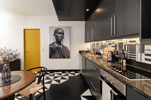 Eine moderne Küche mit Schachbrettfußboden in Schwarz und Weiß, einer gelben Tür und einem großen gerahmten Bild an der Wand.