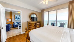 Ett hotellrum med en stor säng, en byrå i trä, en tv och en balkong med utsikt över havet.
