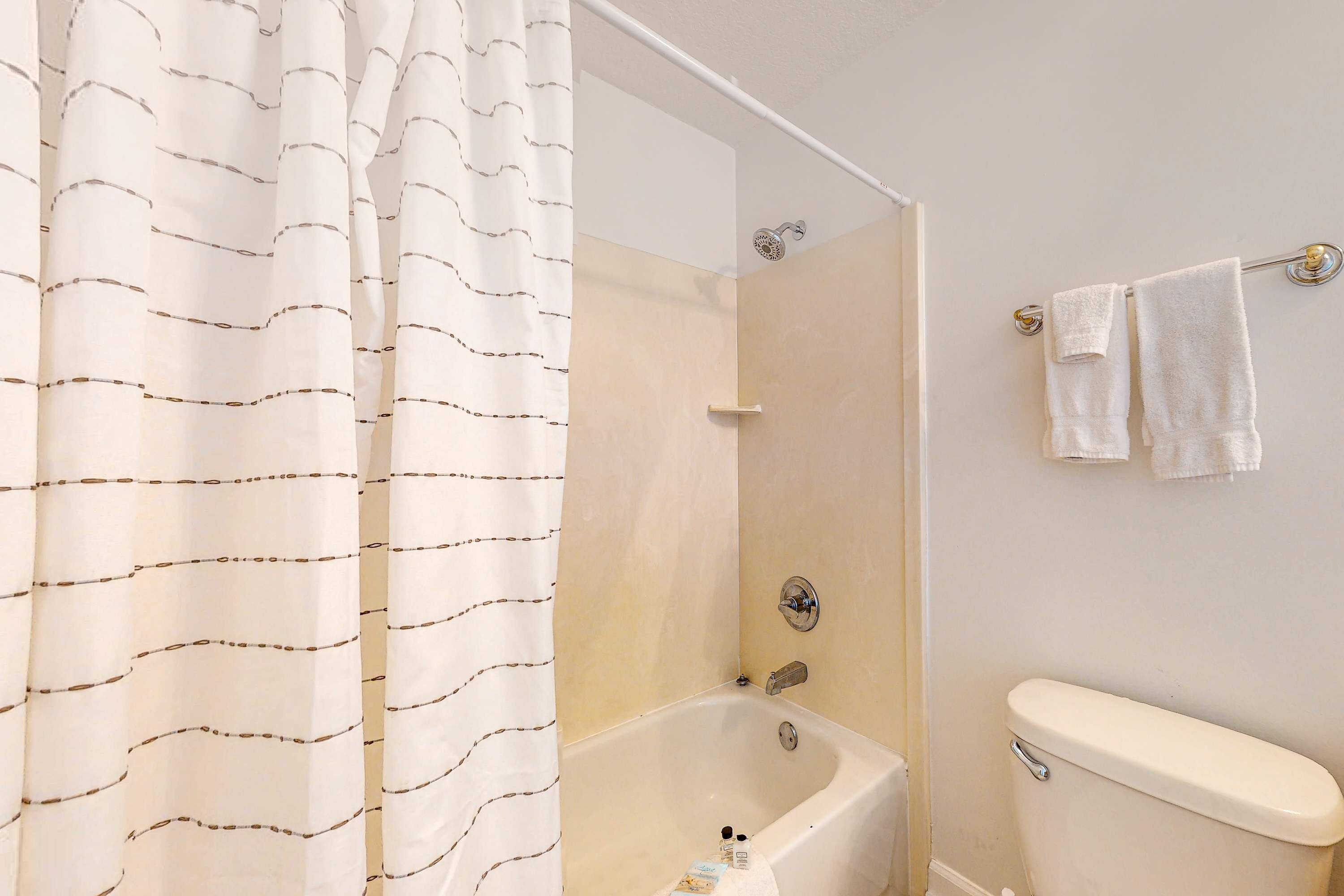 Une salle de bain avec une baignoire, des toilettes et un rideau de douche.