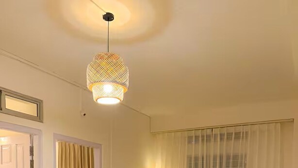 Ett vardagsrum med en soffa, två fåtöljer, ett soffbord och en hängande lampa.