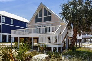 A two-story beachfront house with a balcony, palm trees, and a sandy beach in the background. - Cozy coastal home with plenty of space and close to beach (Navarre)