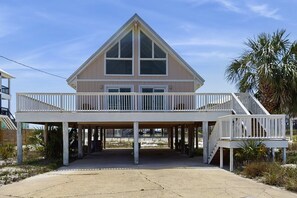 Ein Strandhaus mit Balkon, überdachter Eingangstür und einer Palme.