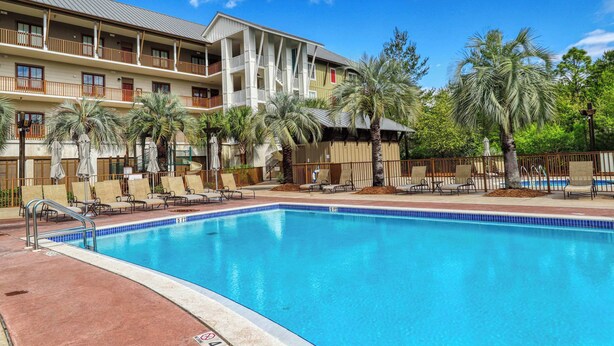 Ein Hotel mit Swimmingpool, mehreren Balkonen und Palmen.