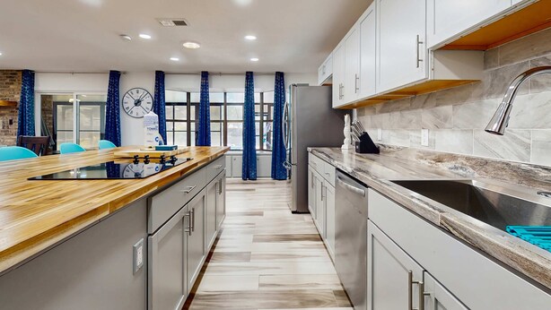 Una cocina moderna con encimera de madera, electrodomésticos de acero inoxidable y salpicadero de mármol.
