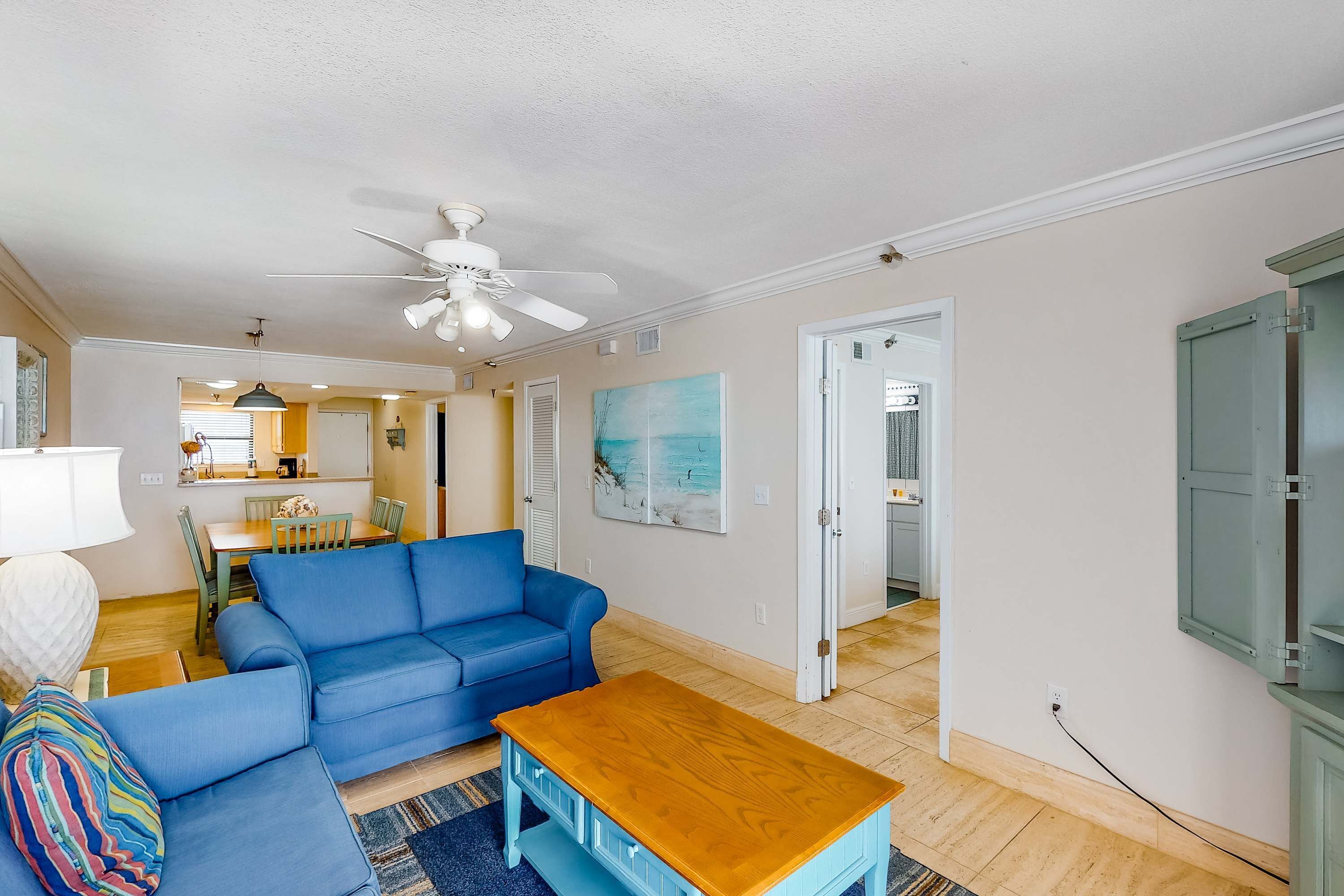 A living room with a blue sofa, a wooden coffee table, and a ceiling fan.
