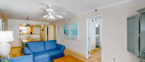 A living room with a blue sofa, a wooden coffee table, and a ceiling fan.