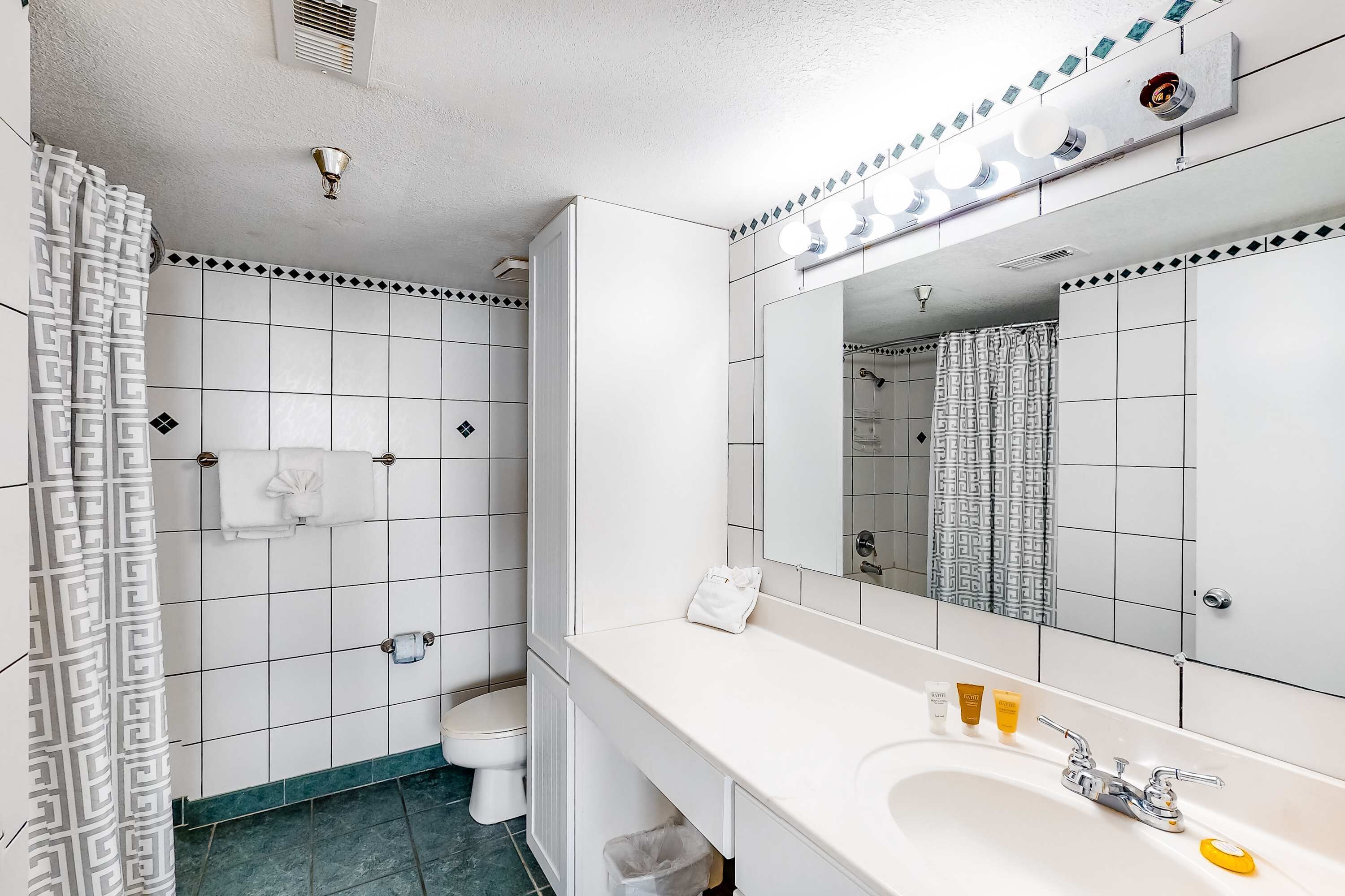 A bathroom with a white sink, mirror, and toilet.