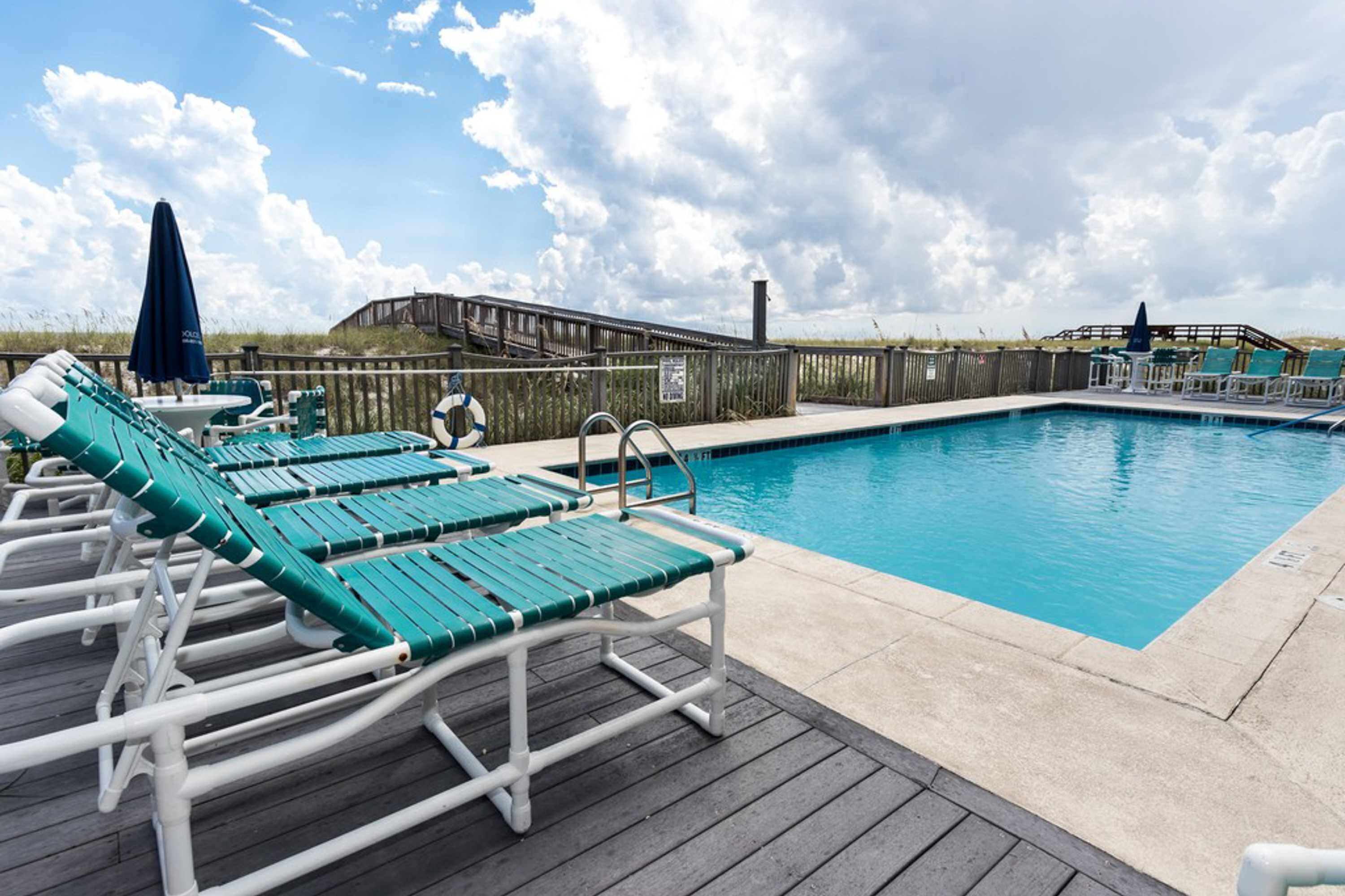A poolside area with lounge chairs and a wooden deck.