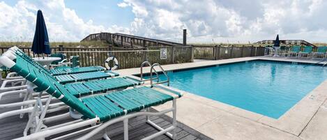 A poolside area with lounge chairs and a wooden deck.