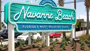 Un cartel da la bienvenida a visitantes a Navarre Beach, Florida, descrito como el lugar más relajante de Florida.