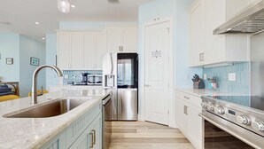 Una cocina moderna con armarios blancos, electrodomésticos de acero inoxidable y una isla grande con un lavamanos.