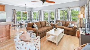 A spacious living area with two sofas, a coffee table, and a dining table set for four. - Tree-lined home with deck and AC - 1 block from the beach, Eastern Lake, and 30A (Santa Rosa Beach)
