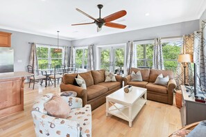 A spacious living area with two sofas, a coffee table, and a dining table set for four. - Tree-lined home with deck and AC - 1 block from the beach, Eastern Lake, and 30A (Santa Rosa Beach)