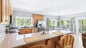 A modern kitchen with granite countertops, wooden cabinets, and a large island. - Tree-lined home with deck and AC - 1 block from the beach, Eastern Lake, and 30A (Santa Rosa Beach)
