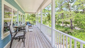 A covered porch with a table and chairs, overlooking a wooded area. - Tree-lined home with deck and AC - 1 block from the beach, Eastern Lake, and 30A (Santa Rosa Beach)