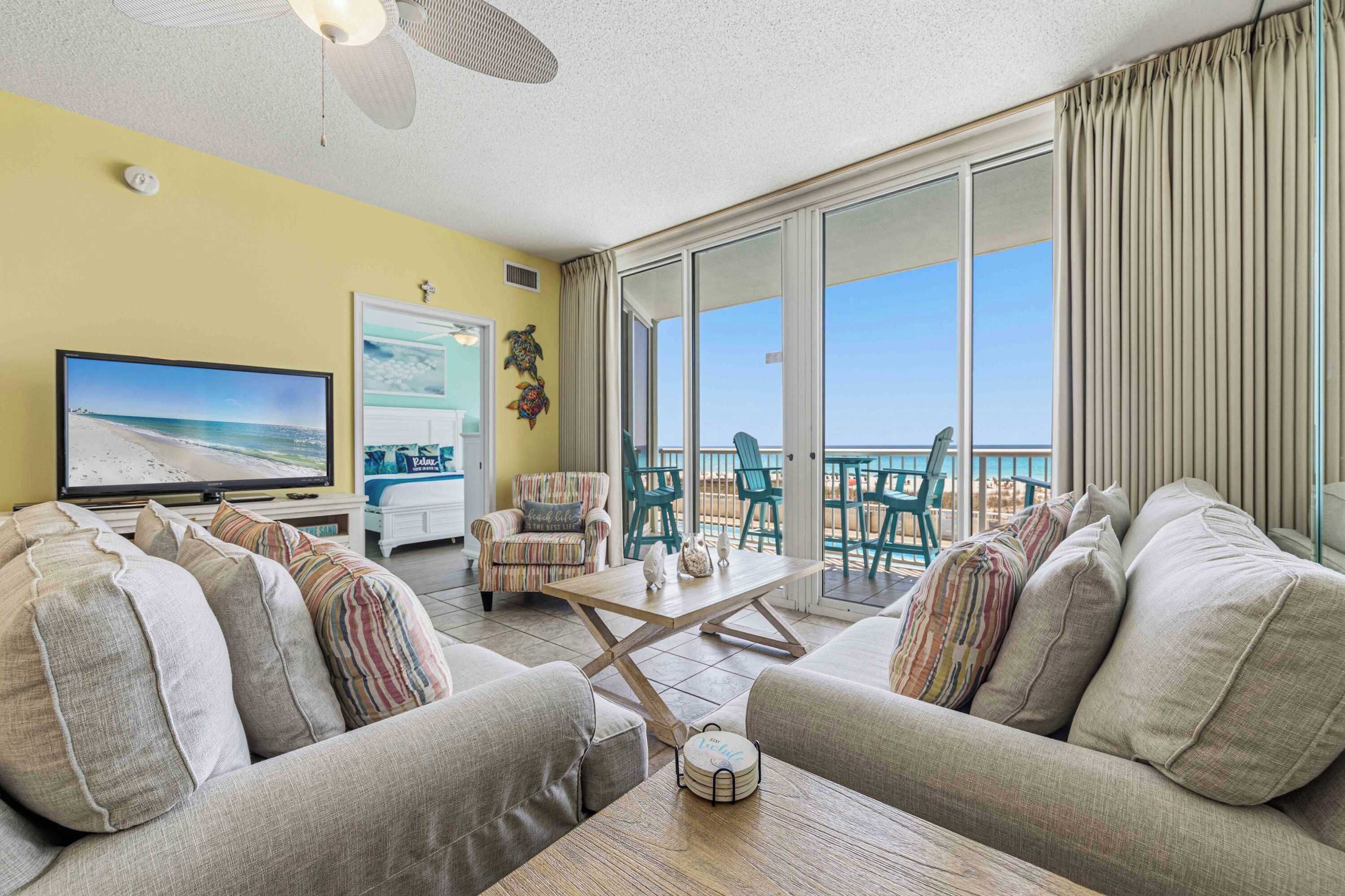 A living room with a TV, sofas, a coffee table, and a balcony with a view.