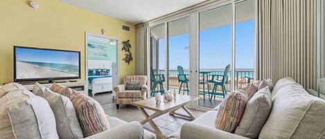 A living room with a TV, sofas, a coffee table, and a balcony with a view.