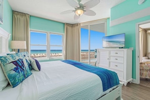 Ein Schlafzimmer mit einem Bett, einem Fernseher und Blick auf den Strand.