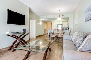 A modern living room with a glass coffee table, a sofa, and a dining area with chairs. - Sixth Floor, Oceanfront Gulf-Front Condo w/ Shared Pool (Fort Walton Beach)