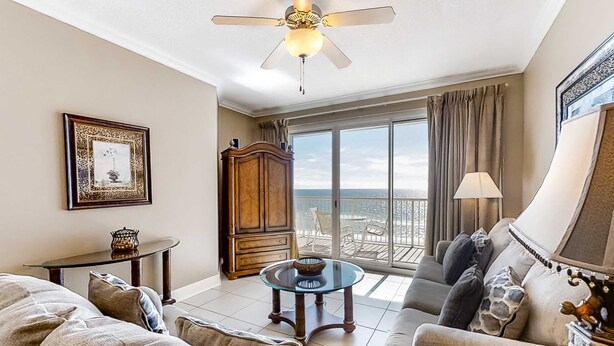 A spacious living room with a large window, a ceiling fan, a wooden cabinet, and a sofa. - Sixth floor Summer Place condo w beach access, shared pool, and more (Fort Walton Beach)
